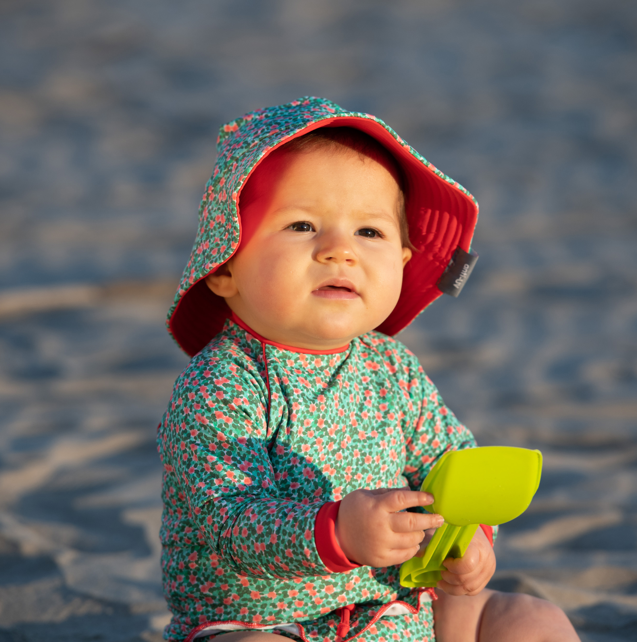 bébé-qui-joue-a-la-plage-protégé-du-soleil